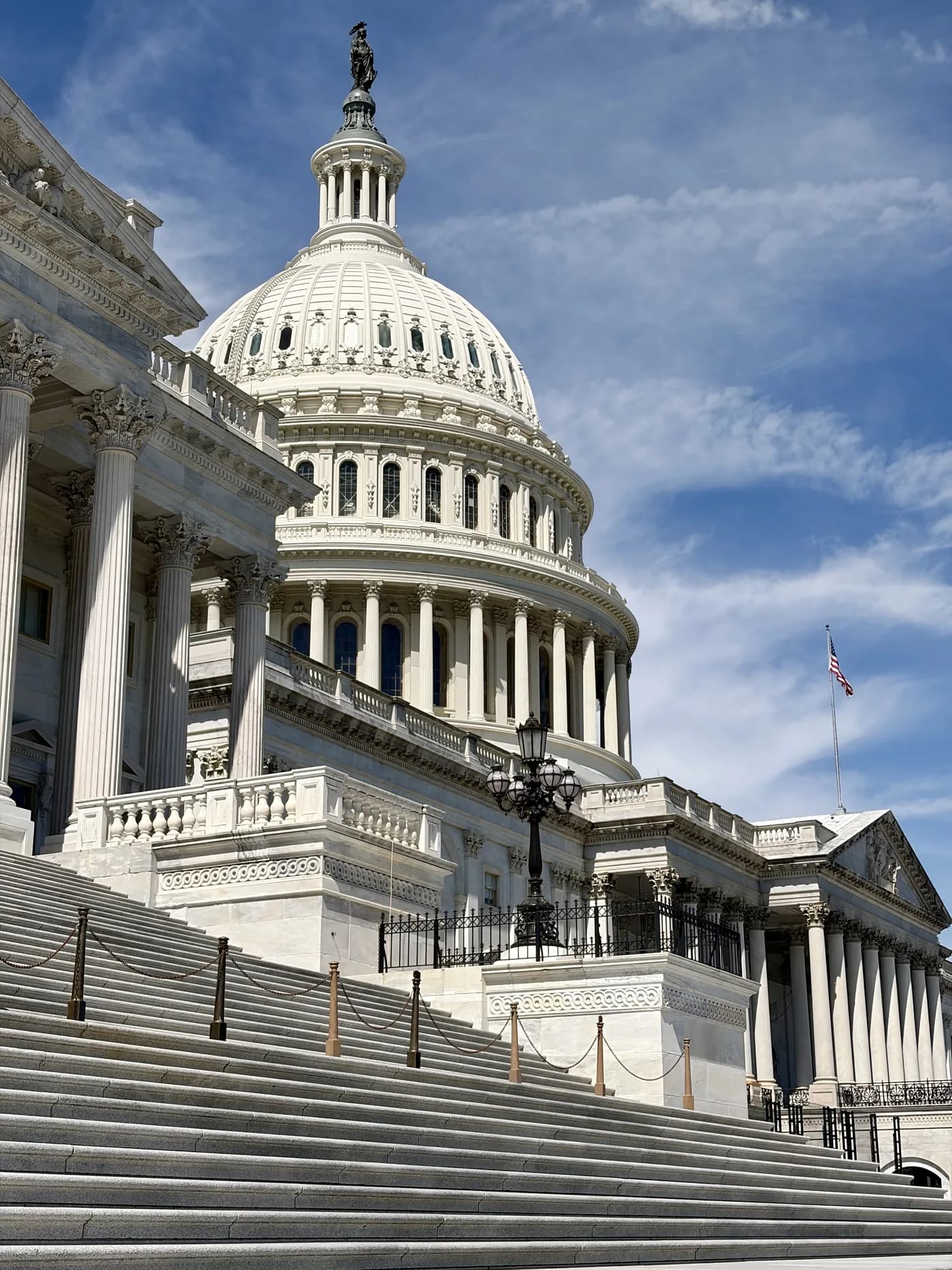 The dome and east steps of the United States Capitol beneath a blue sky